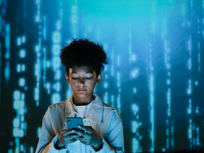 A boy using a mobile phone as streams of data flow around him, symbolizing humans in a data-driven world