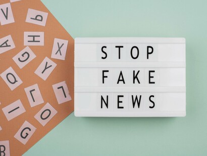 A glowing typographic display reading “Stop fake news,” representing the battle against disinformation in online politics