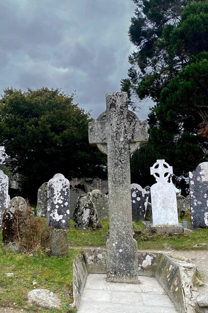 La famosa Torre Redonda de piedra domina el paisaje del antiguo cementerio monástico. Glendalough, Irlanda