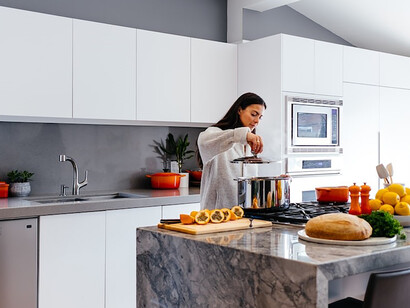 Amidst the artistry of cooking, a woman exudes pure delight with a captivating smile that graces the room