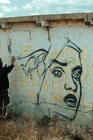 An expressive artist spray-painting the wall of an abandoned building, embodying the spirit of a creative soul