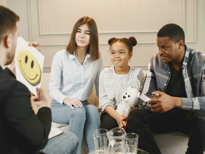 A family and their young child sit together during a therapy session addressing emotional trauma and family healing