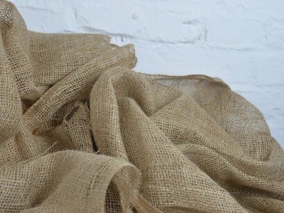 A crumpled piece of sackcloth with visible thin fibers displayed on a white background, representing plant-based materials used in eco-friendly, sustainable fashion