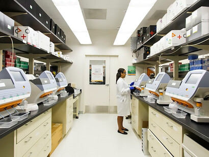 Amidst the cutting-edge technology of the Cancer Genomics Research Laboratory, a skilled technician orchestrates the operation of desktop genomic sequencing machines. At the forefront of DNA genotyping and sequencing, a woman stands, symbolizing the convergence of expertise and advanced research within the National Cancer Institute's Division of Cancer Epidemiology and Genetics (DCEG)