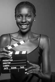 The essence of old Hollywood with a striking image of a black woman holding a clapperboard, embodying the role of a producer with timeless elegance and sophistication
