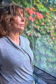 Sylvia Labayru gazes out of the window, her expression reflecting the weight of her past and the complexity of her journey