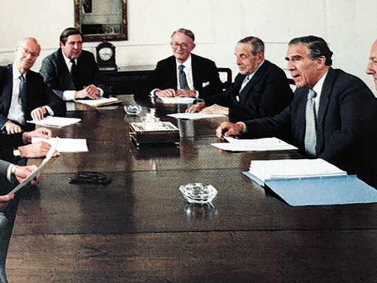 Reunião de diretoria do S.G. Warburg & Co., um influente banco de investimento britânico, por volta de 1980. Warburg foi fundamental na criação do mercado de Eurobonds e era famoso por sua cultura de trabalho intensa, muitas vezes descrita como quase monástica em comparação com outros bancos da época