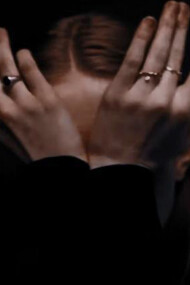 A woman, overwhelmed by emotion, conceals her tear-streaked face with her trembling hands