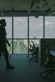 A man in a black jacket walking through an empty office