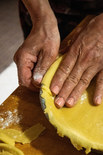 Hands shape pie crust dough on a wooden board, reflecting the care and craftsmanship of traditional home baking