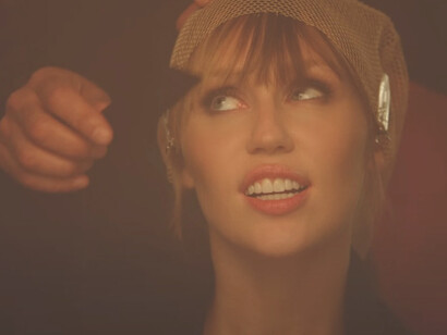 A still of Miley Cyrus from the Easy Lover video captures the moody, cinematic tone of the track