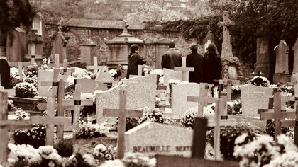 Grupo de pessoas presta homenagem a um ente querido em um cemitério. O enfrentamento da finitude envolve não apenas quem está partindo, mas também aqueles que permanecem e aprendem a conviver com a perda. A morte faz parte da experiência humana, e compreender esse processo pode ajudar a tornar o luto menos solitário