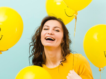 A woman holding smiley face balloons, representing positive thinking and mental health