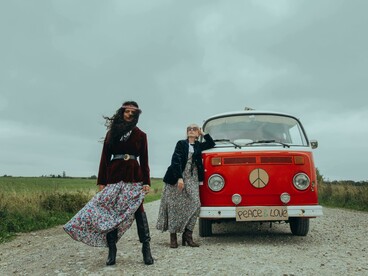 Young people standing near a red Volkswagen van on the road