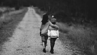 Two kids walking side by side, hugging
