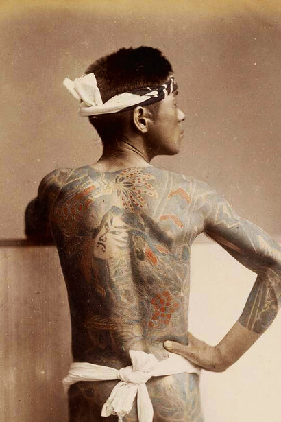 A photograph from the 1890s depicting a man with extensive traditional Japanese tattoos covering his back and arms