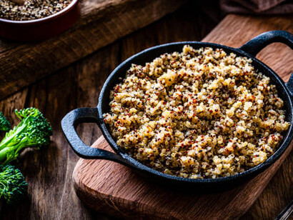 A vibrant quinoa bowl filled with fresh vegetables and garnished with herbs, set against a dark, rustic wooden background