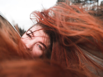 A woman with fiery red hair gracefully leaning out of the car window