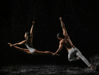 Hombre y mujer practicando acrobacia bajo la lluvia