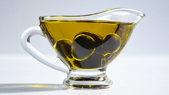 Regador de vidro cheio de azeite de oliva perfumado por azeitonas da estação