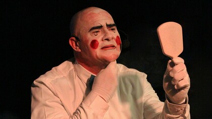 Um artista remove a maquiagem de palhaço diante de um espelho, deixando pouco a pouco o rosto revelar-se por trás da personagem. O gesto simboliza o movimento de abandonar as máscaras sociais e confrontar aquilo que tentamos esconder de nós mesmos — justamente onde a palhaçaria encontra sua força e sua dimensão mais humana