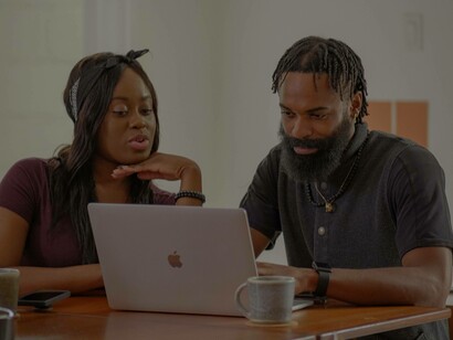 A couple looking eagerly at their laptop as they do some e-commerce live shopping