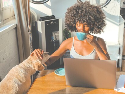 Mulher toma café e trabalha com seu companheiro canino