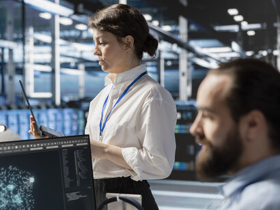 Data center specialist reviewing AI-driven system logs and metrics on a computer