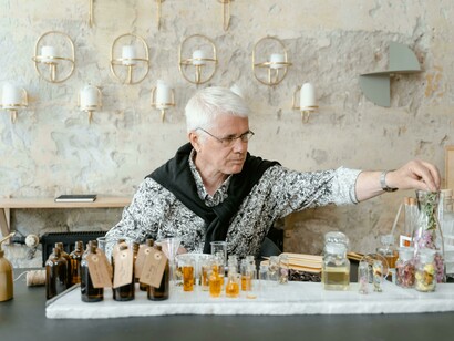 A person sitting at a table with an assortment of perfume bottles