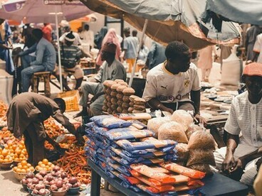 Des vendeurs et des clients dans un marché africain animé, illustrant les moyens de subsistance soutenus par le commerce local et les économies informelles