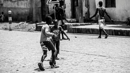 A group of black children playing with a ball on the street