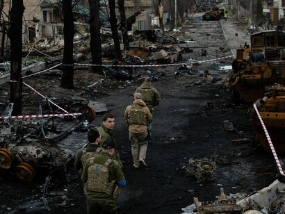 Ein ukrainischer Soldat geht zwischen zerstörten russischen Panzern in Bucha am Stadtrand von Kiew, Ukraine, spazieren