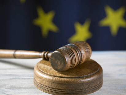 A judge’s gavel placed on a book, with the EU flag behind it, illustrating the tightening grip of EU regulations and bureaucracy over personal freedoms and lifestyle choices