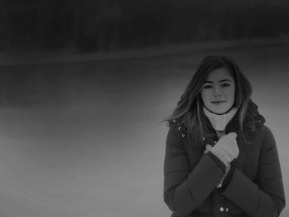 A woman trying to keep warm presents a smile to the photographer even if it seems as though it is forced and against her nature at that moment