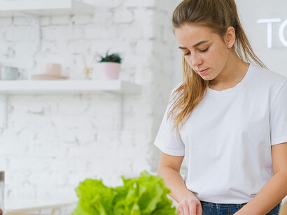 Slicing a fresh orange bell pepper, the woman embraces a nutrient-rich, healthy diet rooted in real, vitamin-packed foods