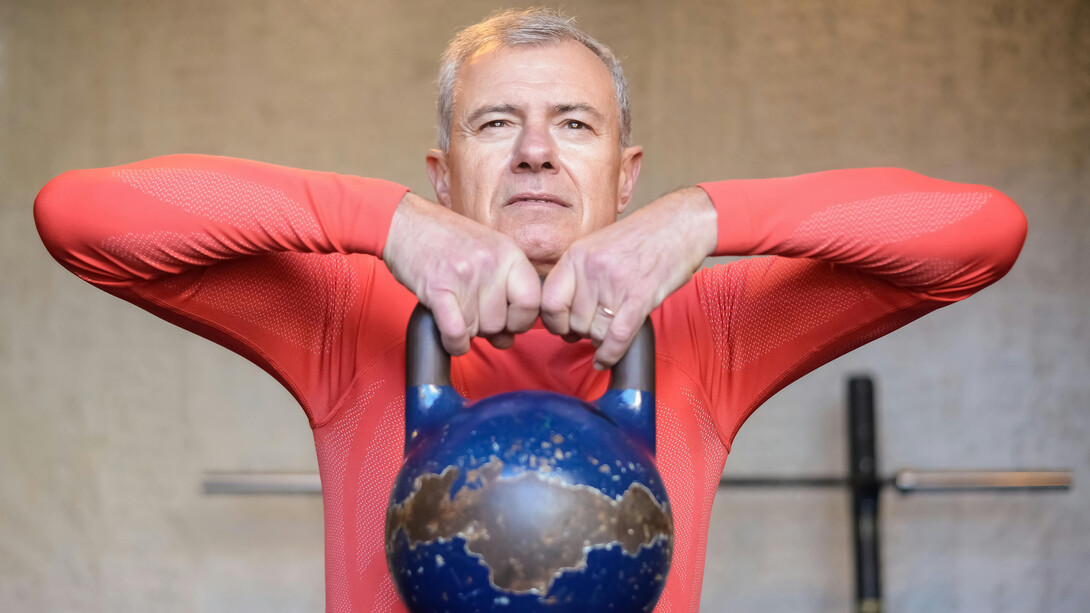 An elderly man lifting a heavy kettlebell, symbolizing longevity, healthspan optimization, and physical resilience