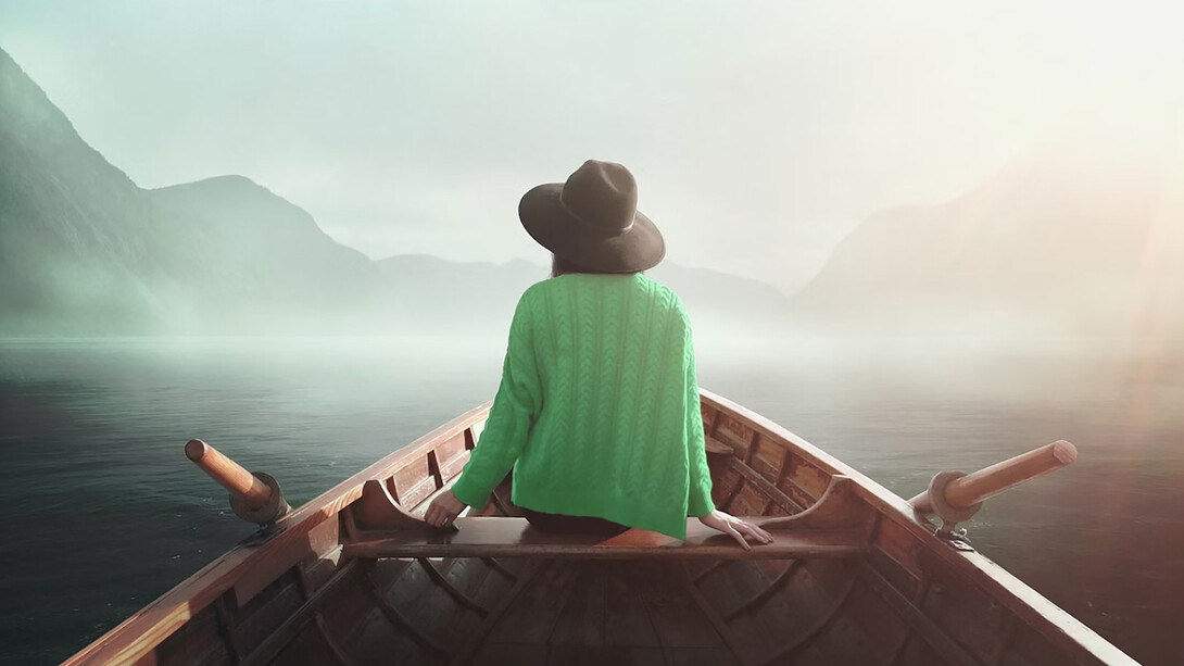 A woman in nature, seated on a boat, embodying the journey to self, mindfulness, and the freedom of life beyond professional roles