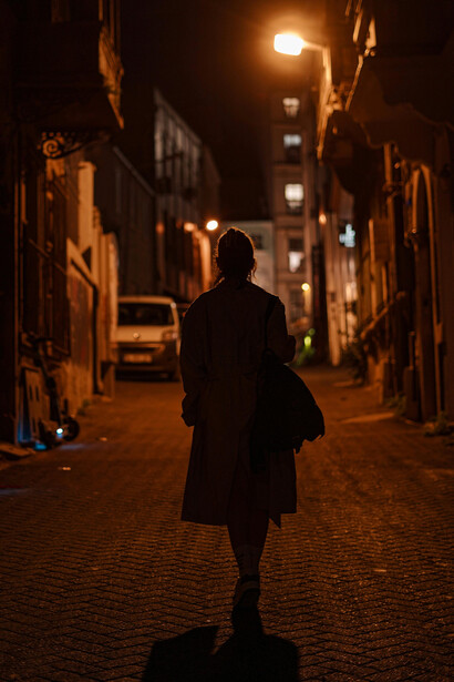 Silhouettes of men on a narrow road, with figures walking along a dark, foggy pavement
