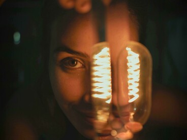 O brilho da lâmpada ilumina parcialmente o rosto feminino, criando uma cena de tensão e revelação. Na música, vir de dia é também exigir verdade e responsabilidade