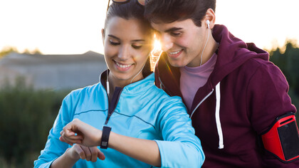Young couple using their smartwatches to track fitness data post-run