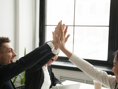 A group of millennial colleagues enthusiastically giving high fives, showcasing collaboration, diversity, and equity in a thriving workplace