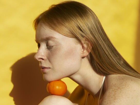 A woman with naturally freckled skin in warm daylight, reflecting the importance of protecting vulnerable skin from UV damage