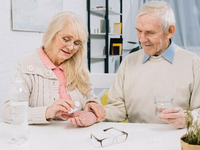A senior couple carefully sorts and takes their medication together
