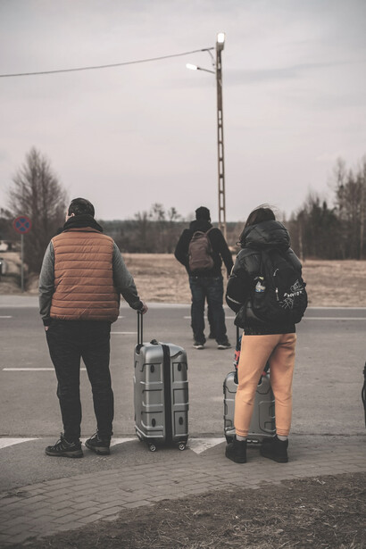 A group of people standing next to each other with luggage, fleeing Ukraine
