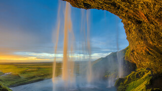 Vista lateral de la cascada Seljalandsfoss durante una puesta de sol, región de Suðurland, Islandia