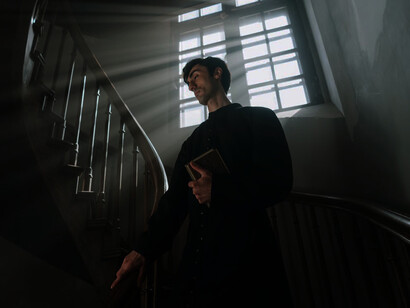 Within the priest's gentle touch resides the ancient scripture, a token of antiquity