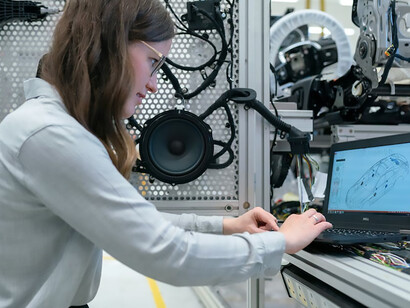 A skilled female engineer passionately engrossed in her work, maneuvers through the workshop with expertise, demonstrating both technical prowess and a commitment to her craft