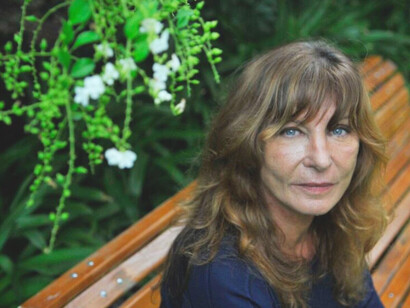 In the serene garden, Sylvia Labayru reflects on her tumultuous past, her gaze capturing the complexity of her experiences