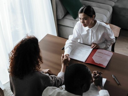 Vista de cima, a fotografia mostra participantes de uma reunião profissional apertando as mãos sobre uma mesa, em meio a documentos. A cooperação entre profissionais e instituições pode contribuir para a continuidade do acompanhamento social e para a construção de oportunidades de reinserção