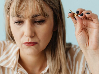 A woman holding a paperclip while contemplating the message of her soul
